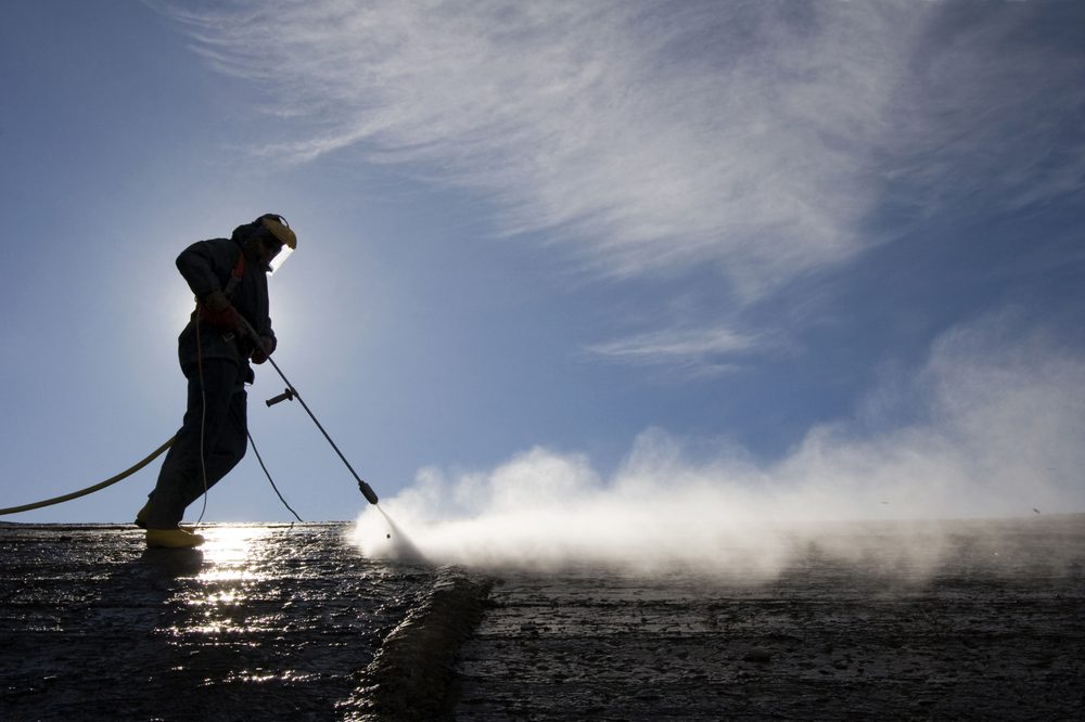 High pressure cleaning an exterior surface against a blue sky