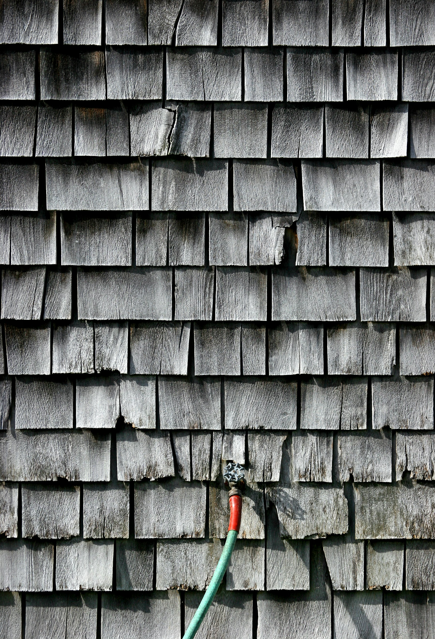 Garden hose against a weathered house exterior